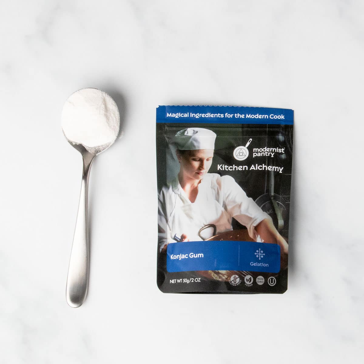 black and bluepouch of konjac powder with sample of white powder on large metal spoon