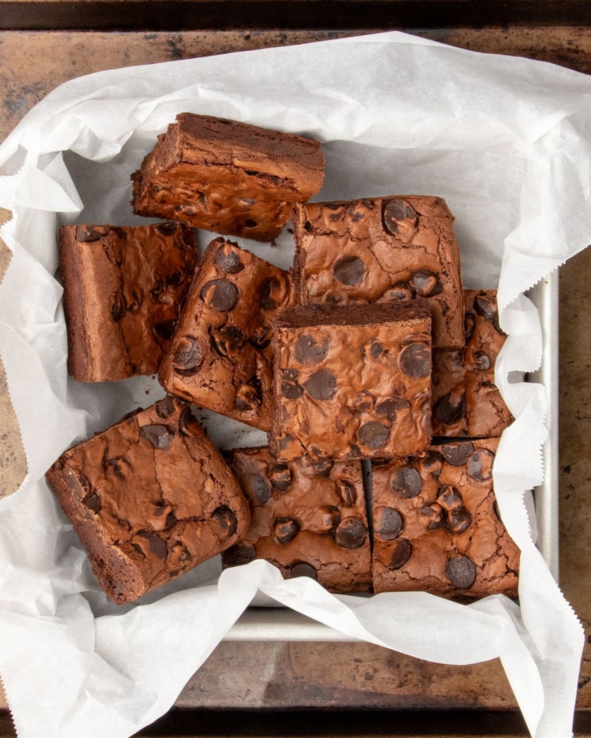 Thick, fudgy brownies cut into squares in a parchment-lined pan, ready to serve