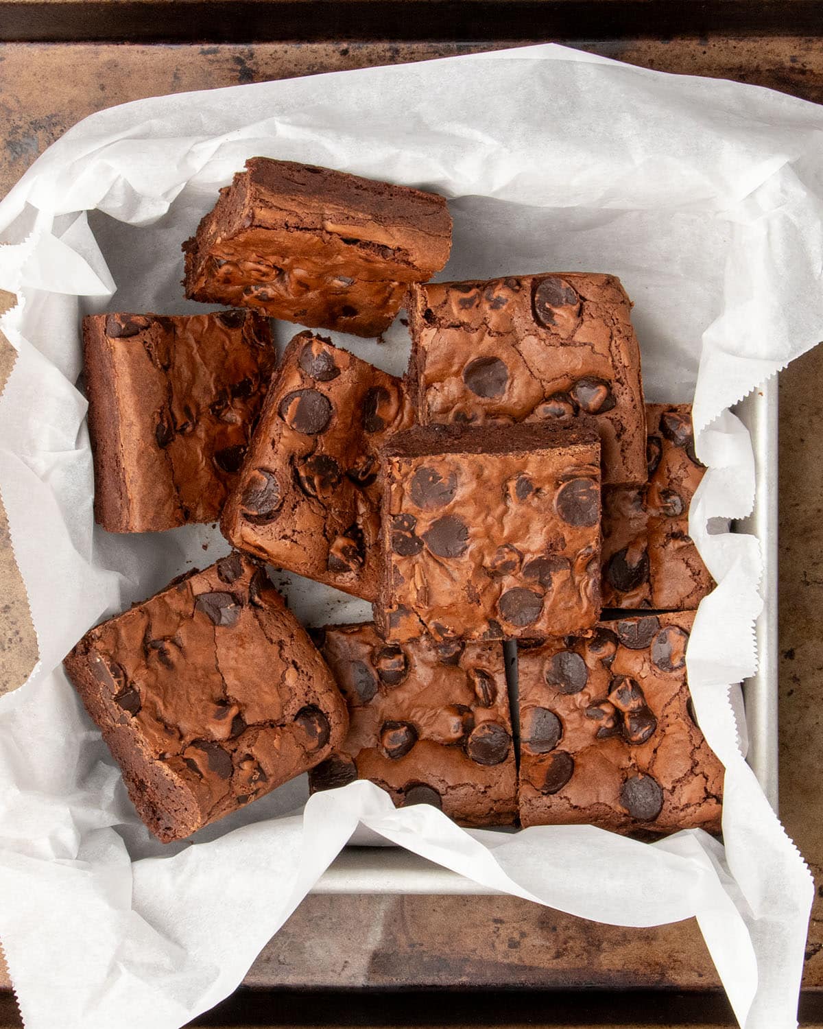 Thick, fudgy brownies cut into squares in a parchment-lined pan, ready to serve