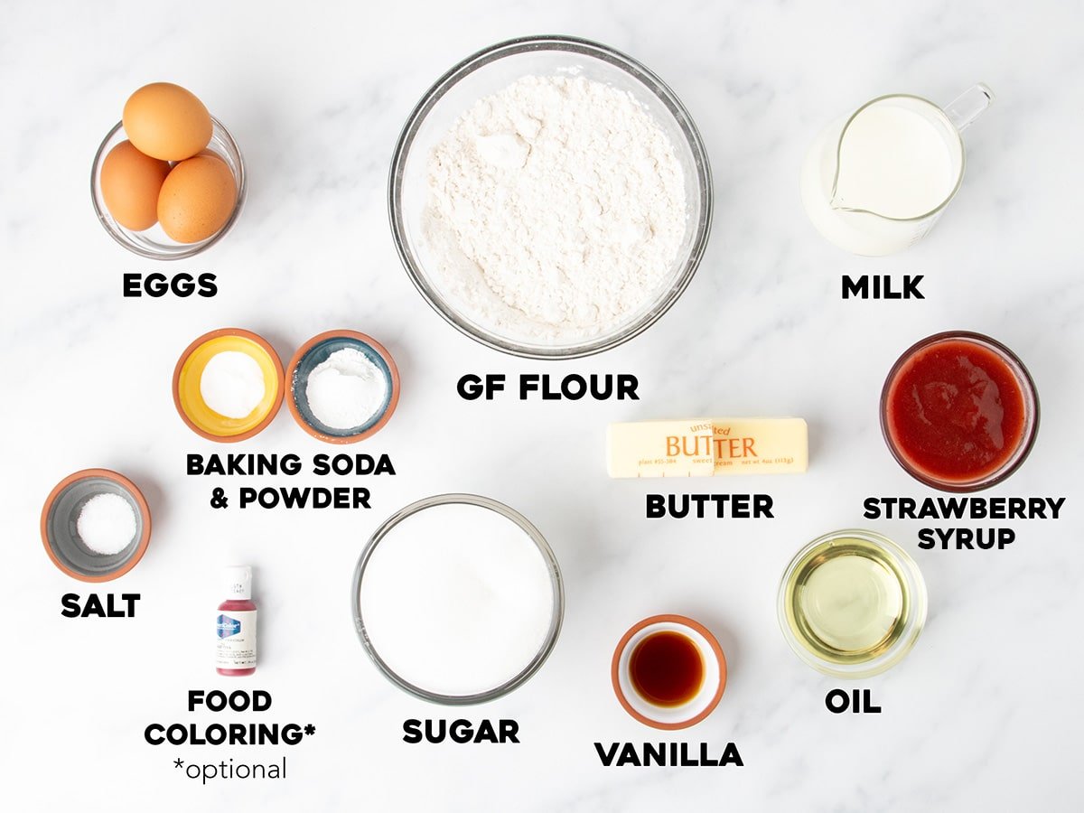 Overhead view of measured and labeled ingredients for gluten free strawberry cake on a white surface