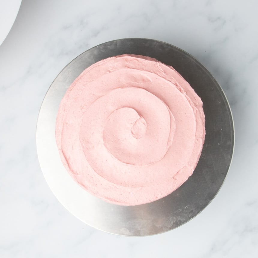 Top view of cake covered in an even layer of pink frosting.