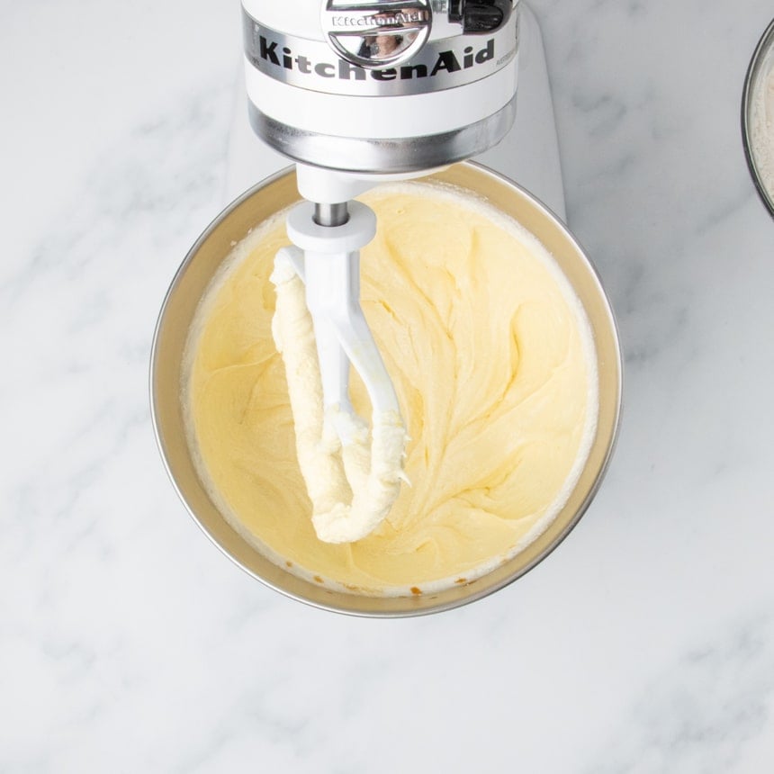 Pale yellow creamed butter and eggs mixture in a stand mixer bowl.