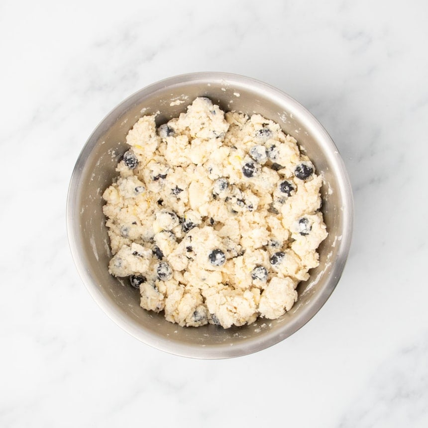 The mixture in the bowl after being stirred, with wet and dry ingredients combined into a crumbly dough.