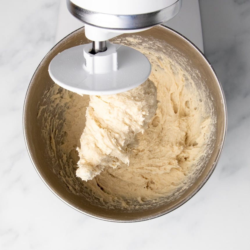 shaggy light tan raw soft pretzel dough with white dough hook in stand mixer bowl