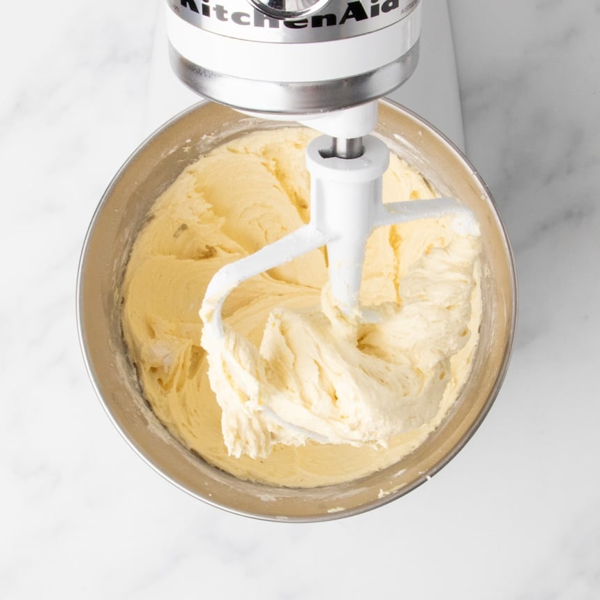 Smooth, thick apple cake batter with flour added in stand mixer bowl with paddle attachment.
