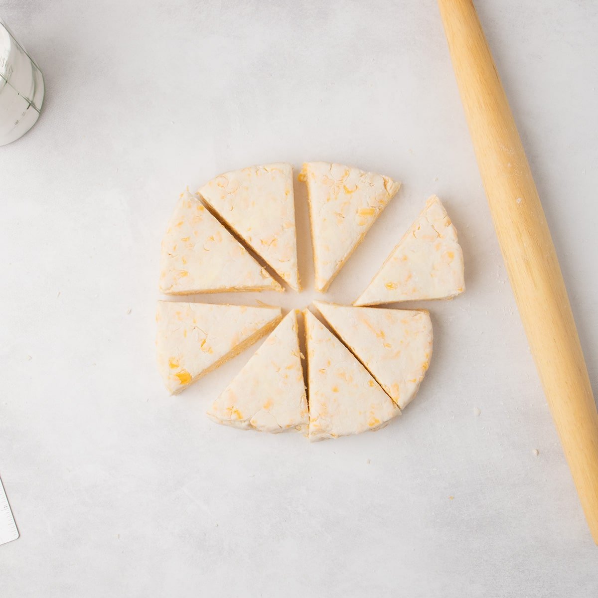 The round raw dough has been cut into 8 equal triangular wedges arranged in a circle on the work surface.