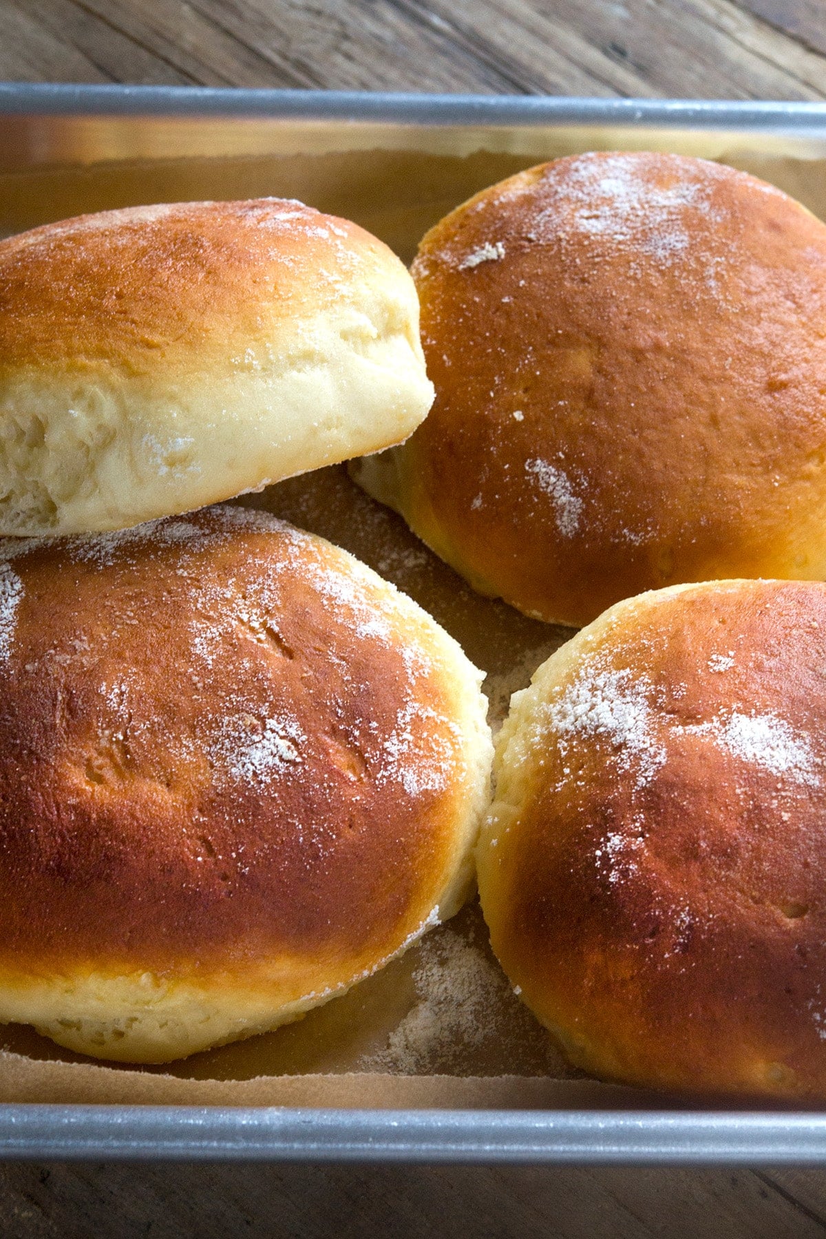 A close up of a gluten free Hawaiian bread rolls in a pile on a tray.