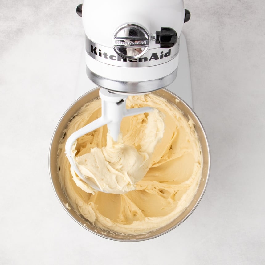 Stand mixer with paddle attachment mixing a thick, smooth dough inside a metal bowl.