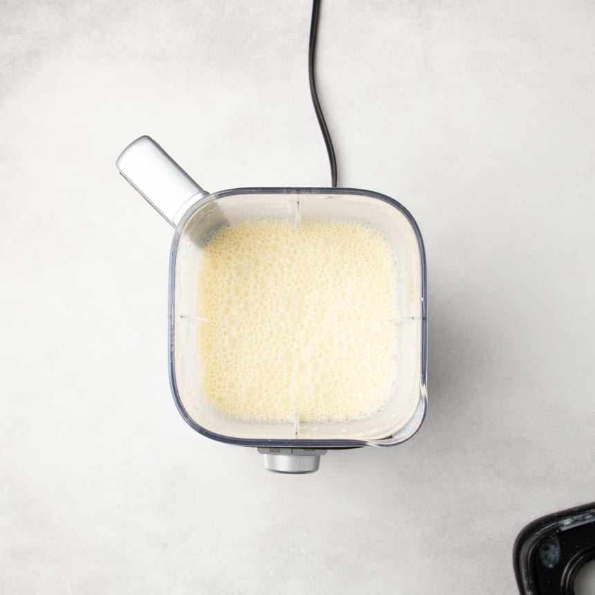 Blender container filled with smooth, foamy light yellow raw batter.