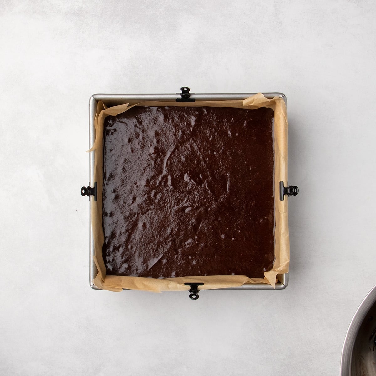 Dark chocolate batter spread in a parchment-lined rectangular baking pan.