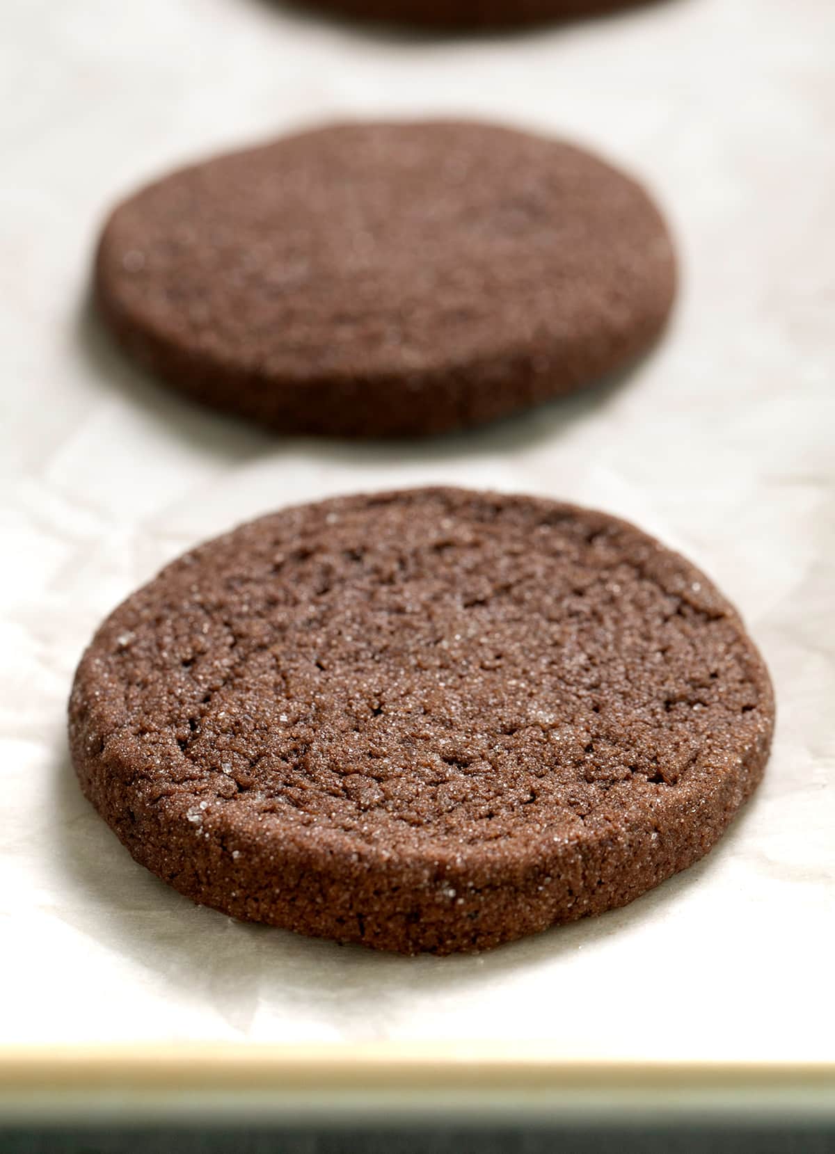 Baked chocolate cookie with sugar coating on white paper on tray