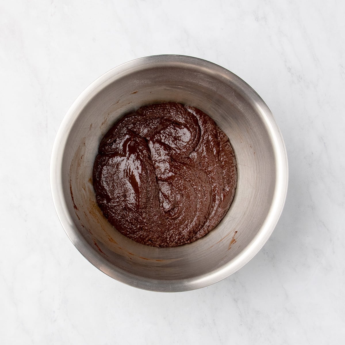 Thick, soft raw chocolate cookie dough in a metal mixing bowl.