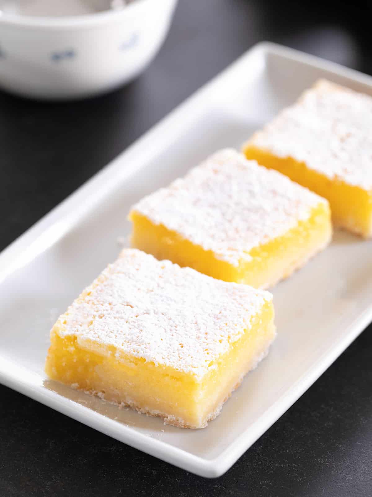Three lemon bars on a white platter