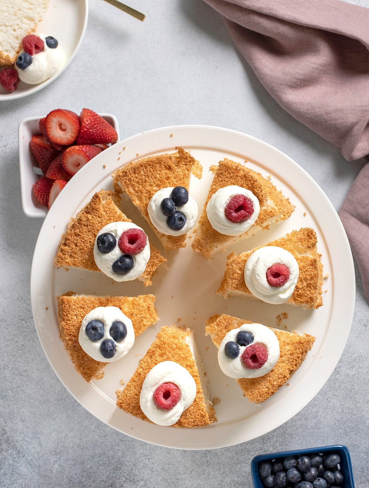 Overhead image of 7 slices of light brown crusted gluten free angel food cake on a white cake plate