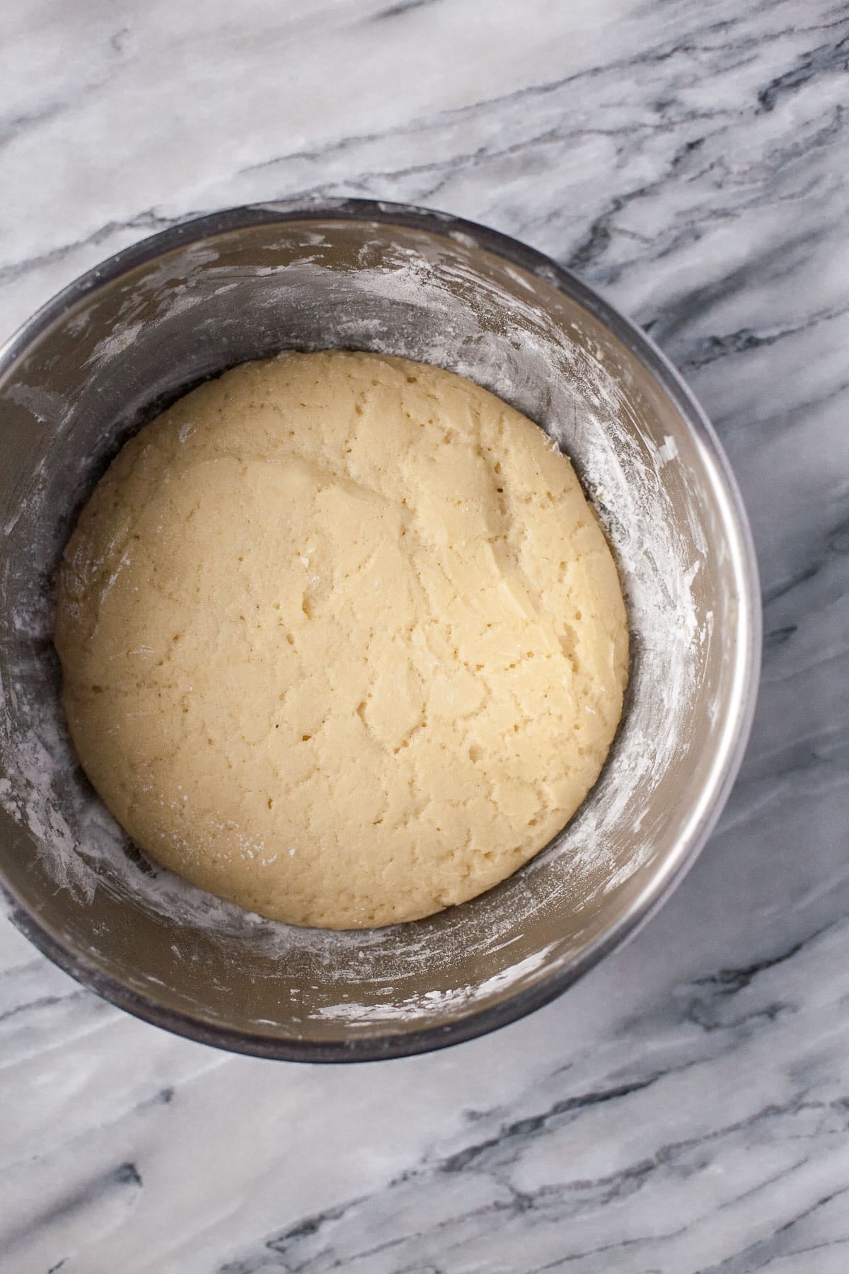 raw risen ball of paleo pizza dough in round metal mixing bowl