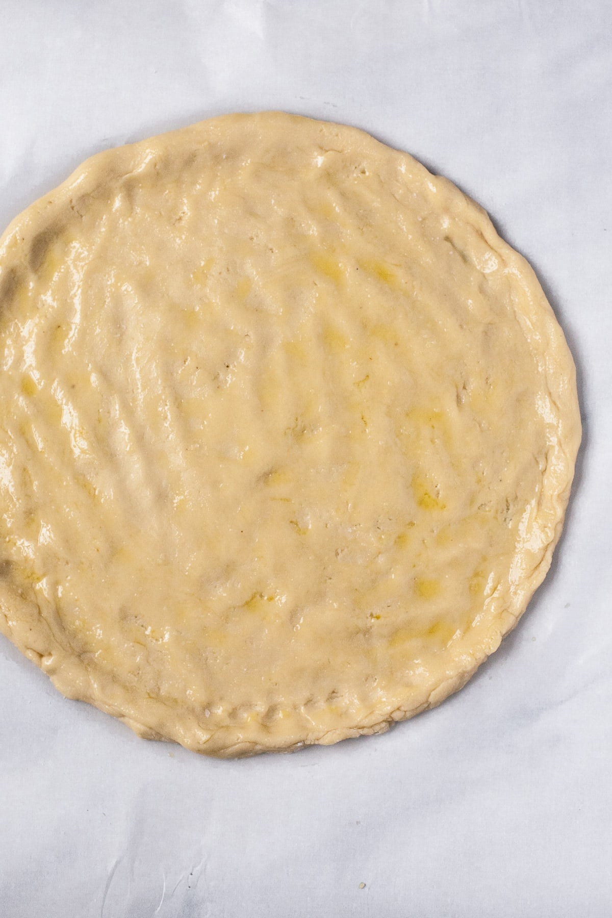 shaped round of light tan paleo pizza dough with raised edge