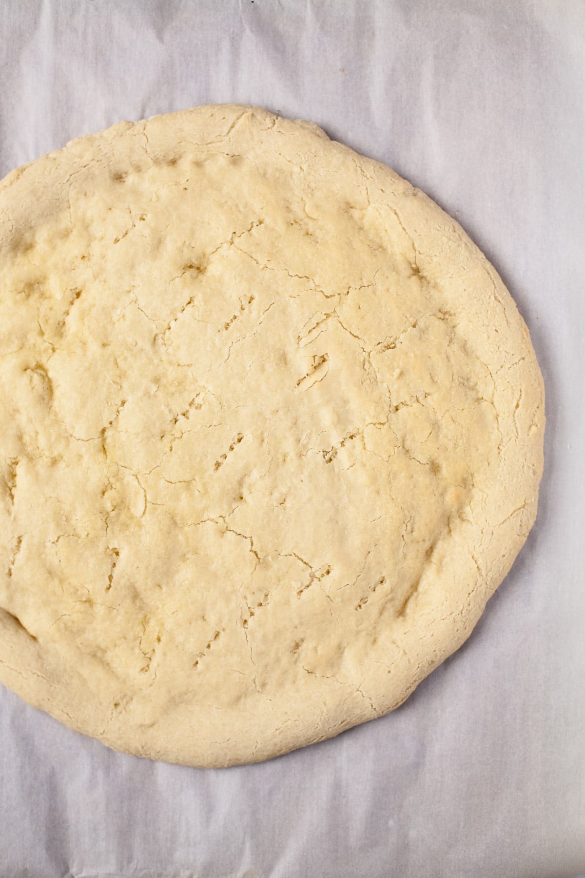 same shaped pizza dough, pierced with a fork and partially baked into a pale tan crust