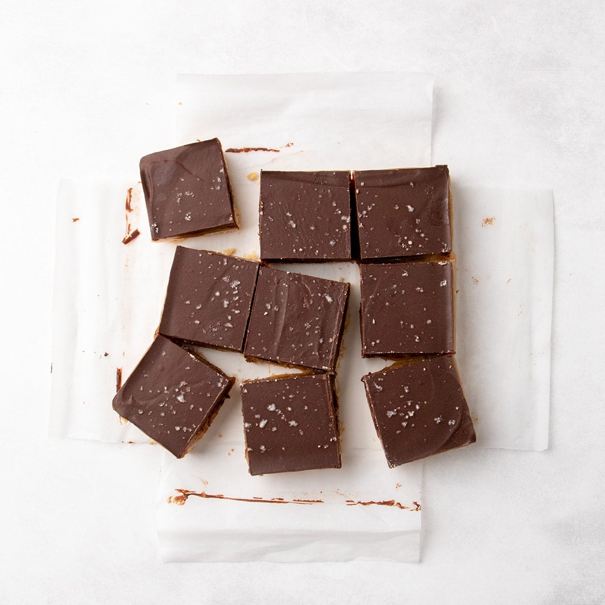 Cut chocolate-topped shortbread squares with coarse salt on parchment paper.
