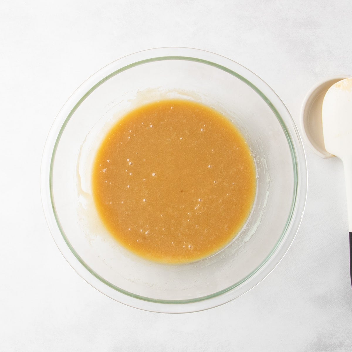 Smooth caramel-colored mixture in a clear glass mixing bowl.
