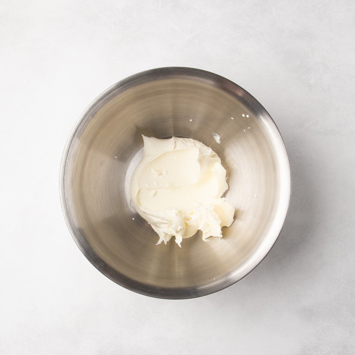 Pale cream-colored mascarpone cheese in a metal mixing bowl.