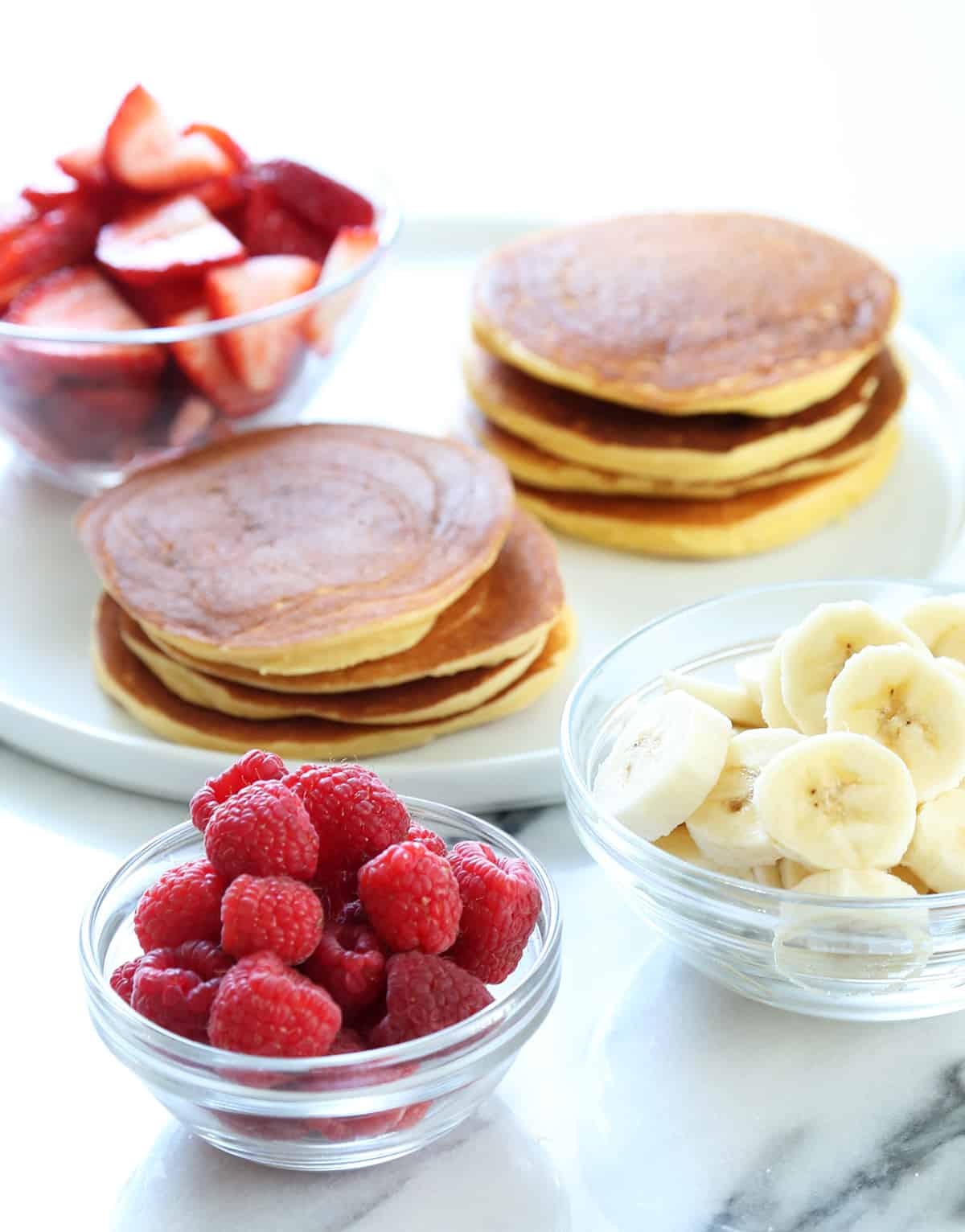 Coconut flour pancakes raw on a skillet, cooked, and in a stack with fruit