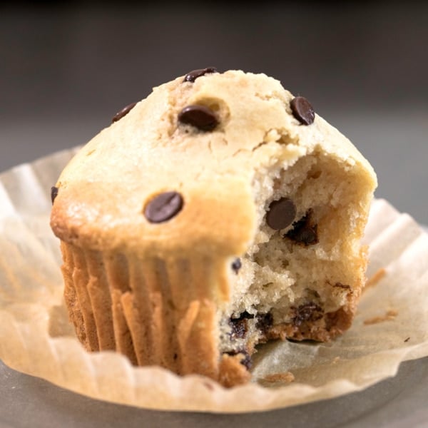 closeup image of lightly golden brown almond flour muffins with mini chocolate chips in open brown muffin wrapper