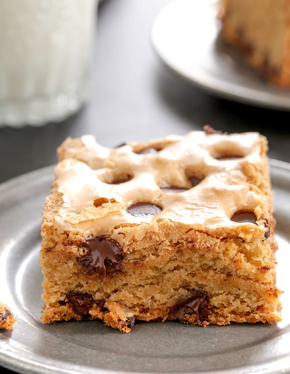 single brown cookie bar square with chocolate chips on small round pewter plate