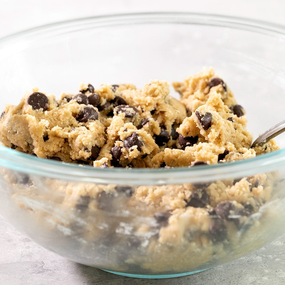 glass bowl of raw light brown cookie dough with chocolate chips