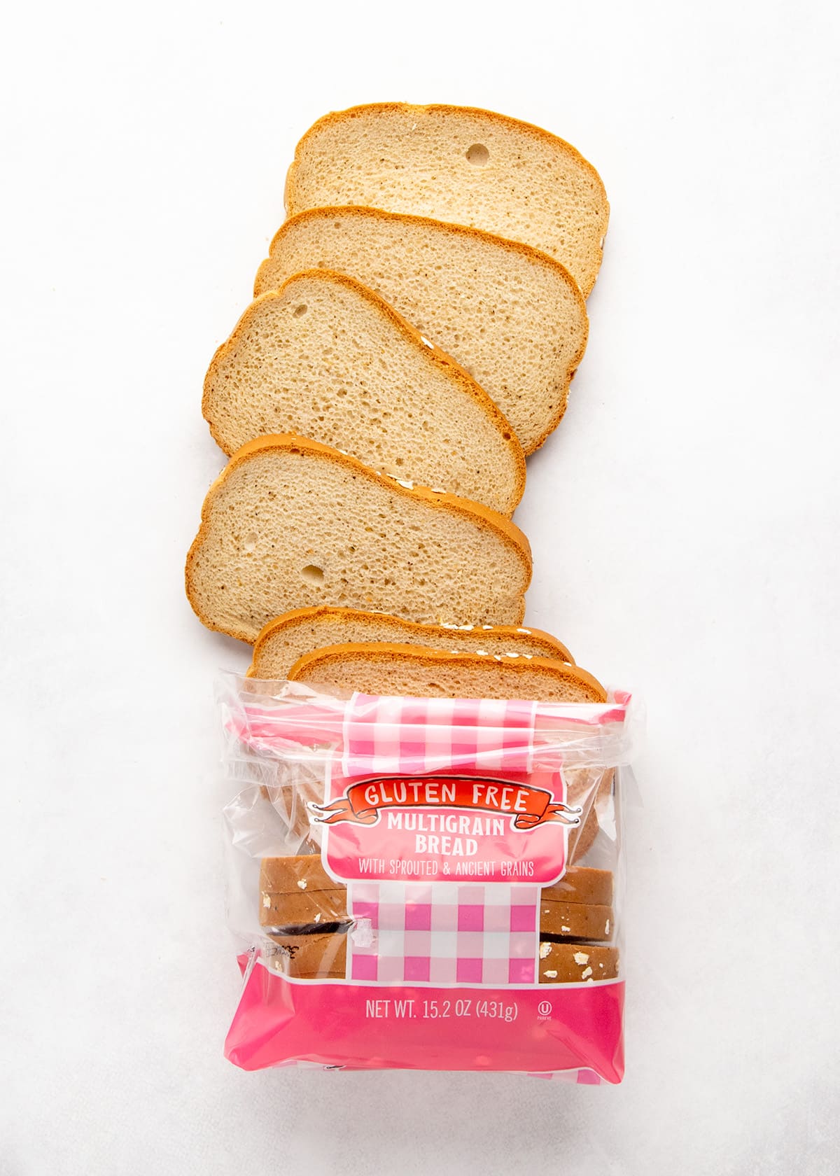 loaf of packaged bread with about half the slices visible outside the plastic and the other half inside, all in a plastic package on a white surface