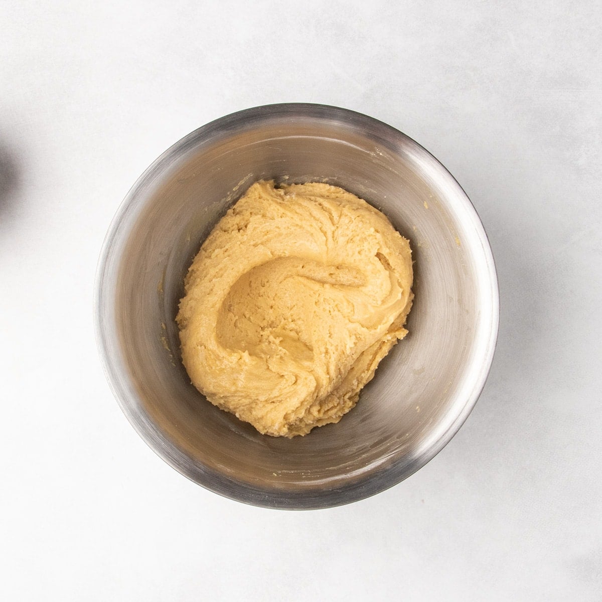 Smooth, cohesive light tan cookie dough in a metal mixing bowl.