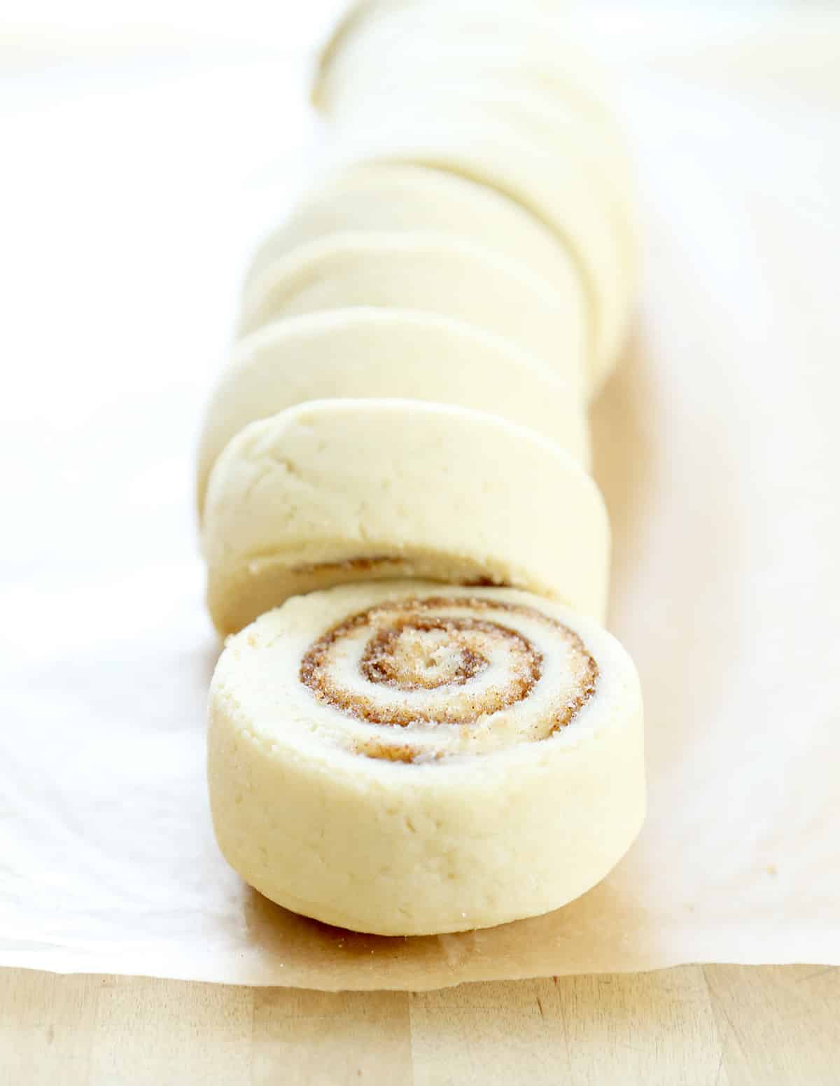 Cinnamon bun dough slices on brown surface