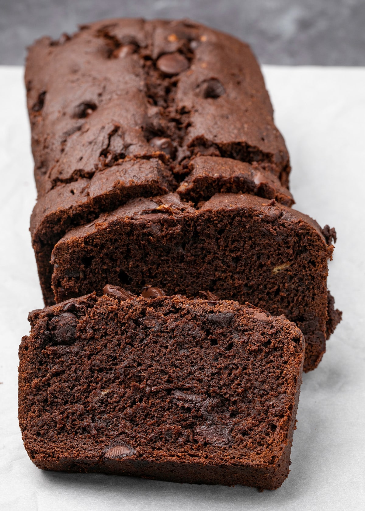 Brown quick bread loaf sliced 3 times on white paper