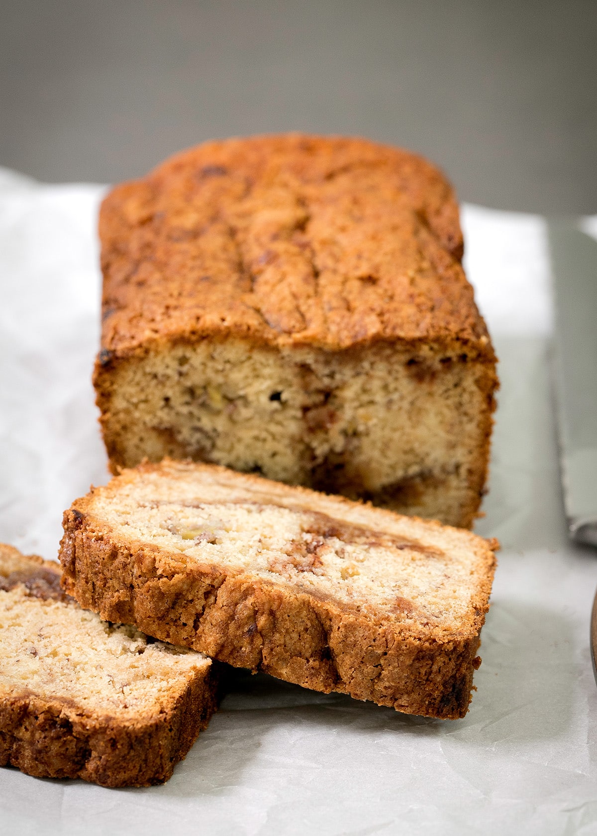 Two thick slices of golden-brown bread sit in front of a loaf with a cracked, browned top.