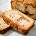 Closeup image of two thick slices of golden-brown bread rest in front of a partially sliced loaf, revealing dark swirls through the crumb.