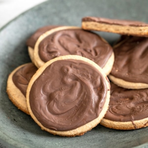 closeup image of 7 gluten free digestive biscuits with chocolate coating on small gray plate