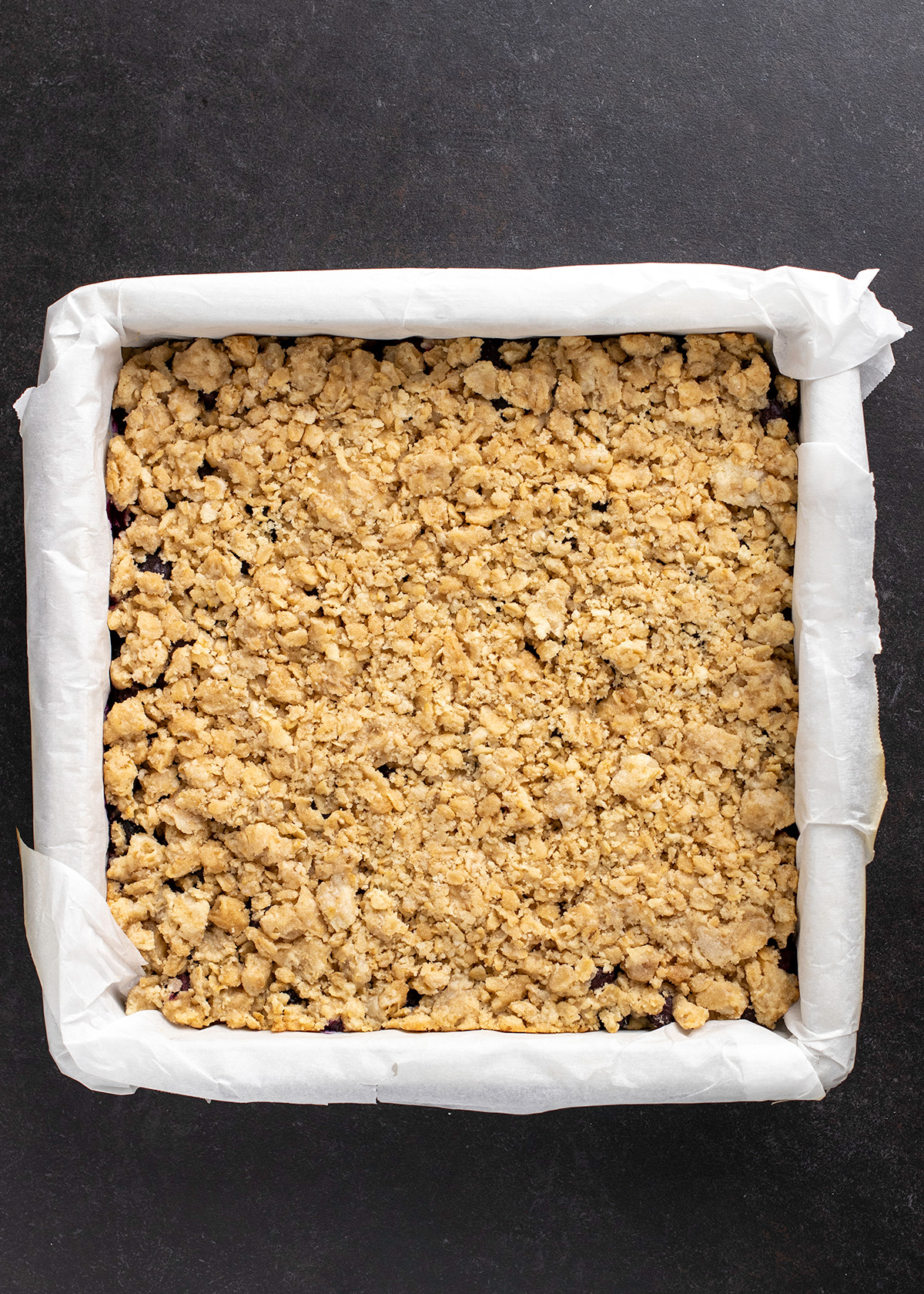 Overhead image of baked crumble in white paper liner in square baking pan