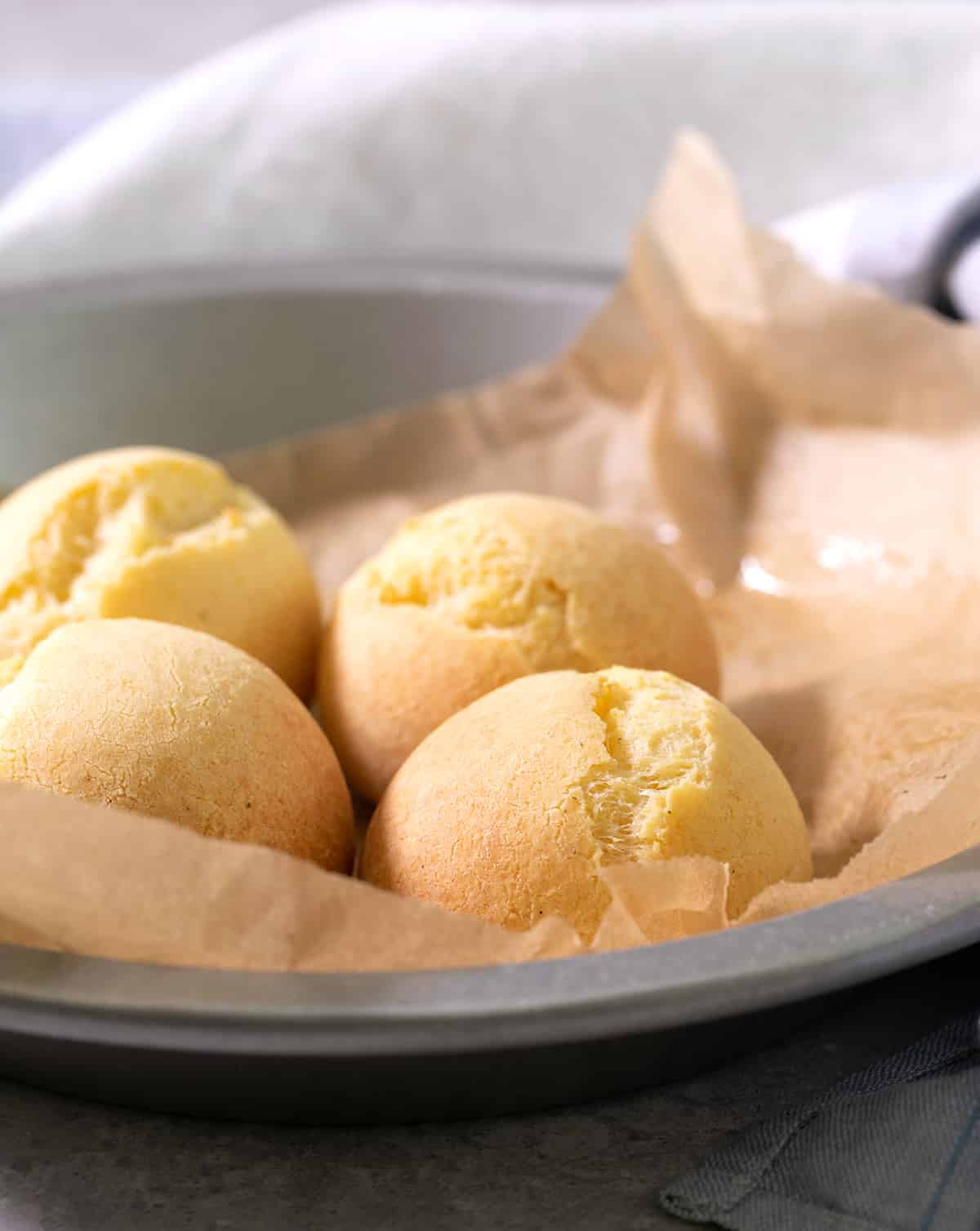 A round tin with brown paper and 4 pan de bono rolls