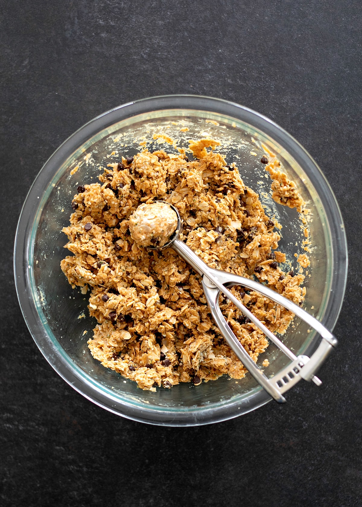 A glass mixing bowl filled with the combined protein ball ingredients.