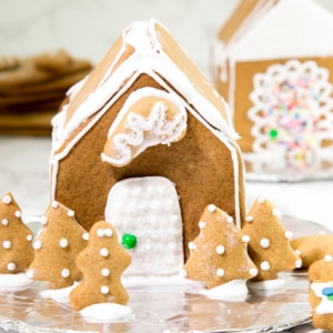 closeup image of gluten free gingerbread house fully decorated with white royal icing and a green sixlet candy as a doorknob