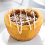 closeup image of orange outside with brown sugar and cinnamon inside of a gluten free pumpkin cinnamon roll on a small white plate