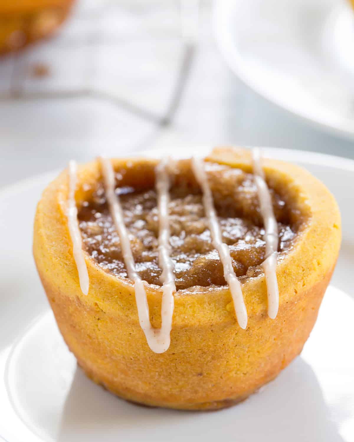 A close up of a pumpkin cinnamon roll on a white plate