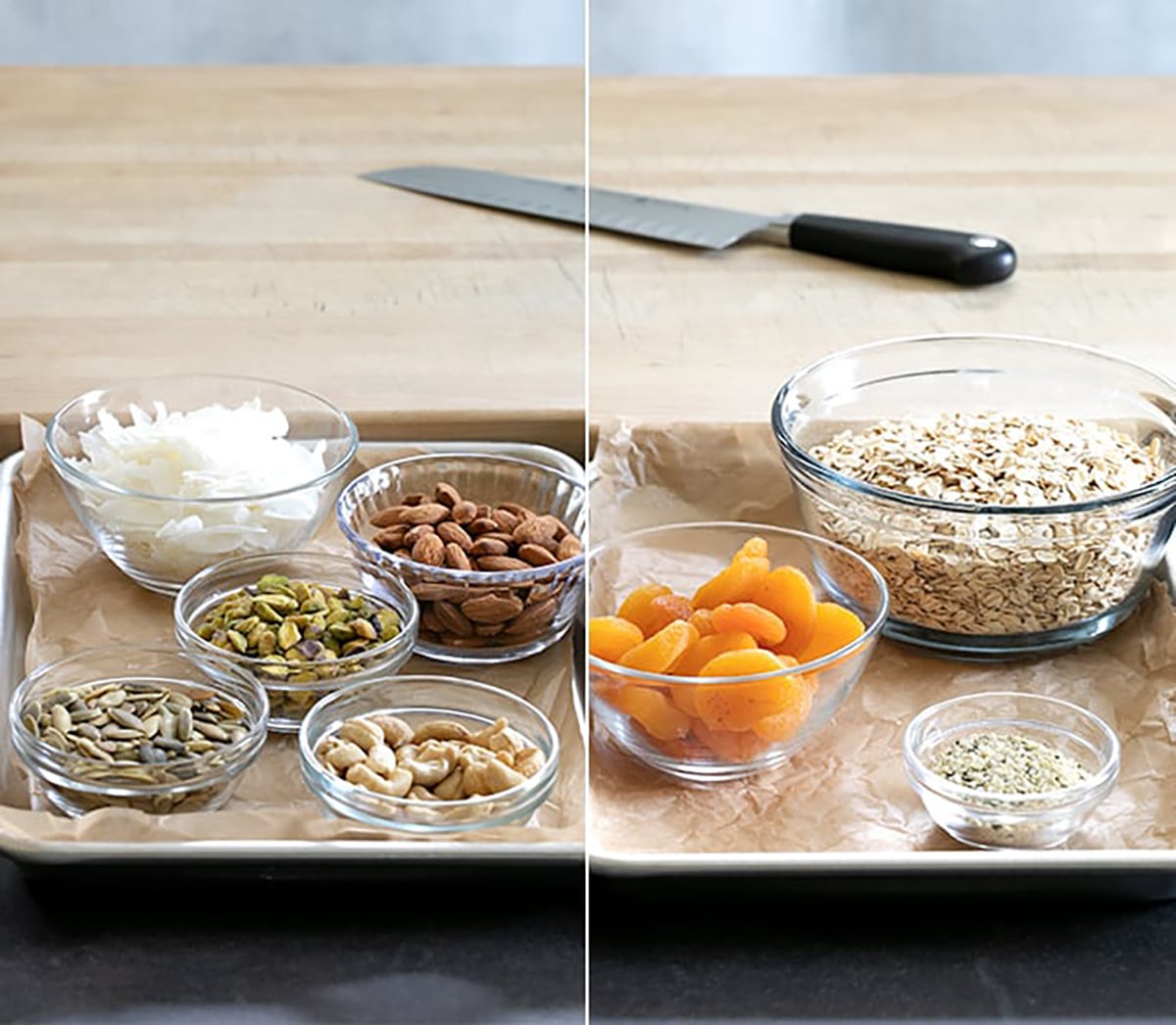 Bowls of rolled oats, dried apricots, coconut flakes, almonds, pistachios, cashews, sunflower seeds, and a small bowl of seeds sit on parchment-lined baking sheets.