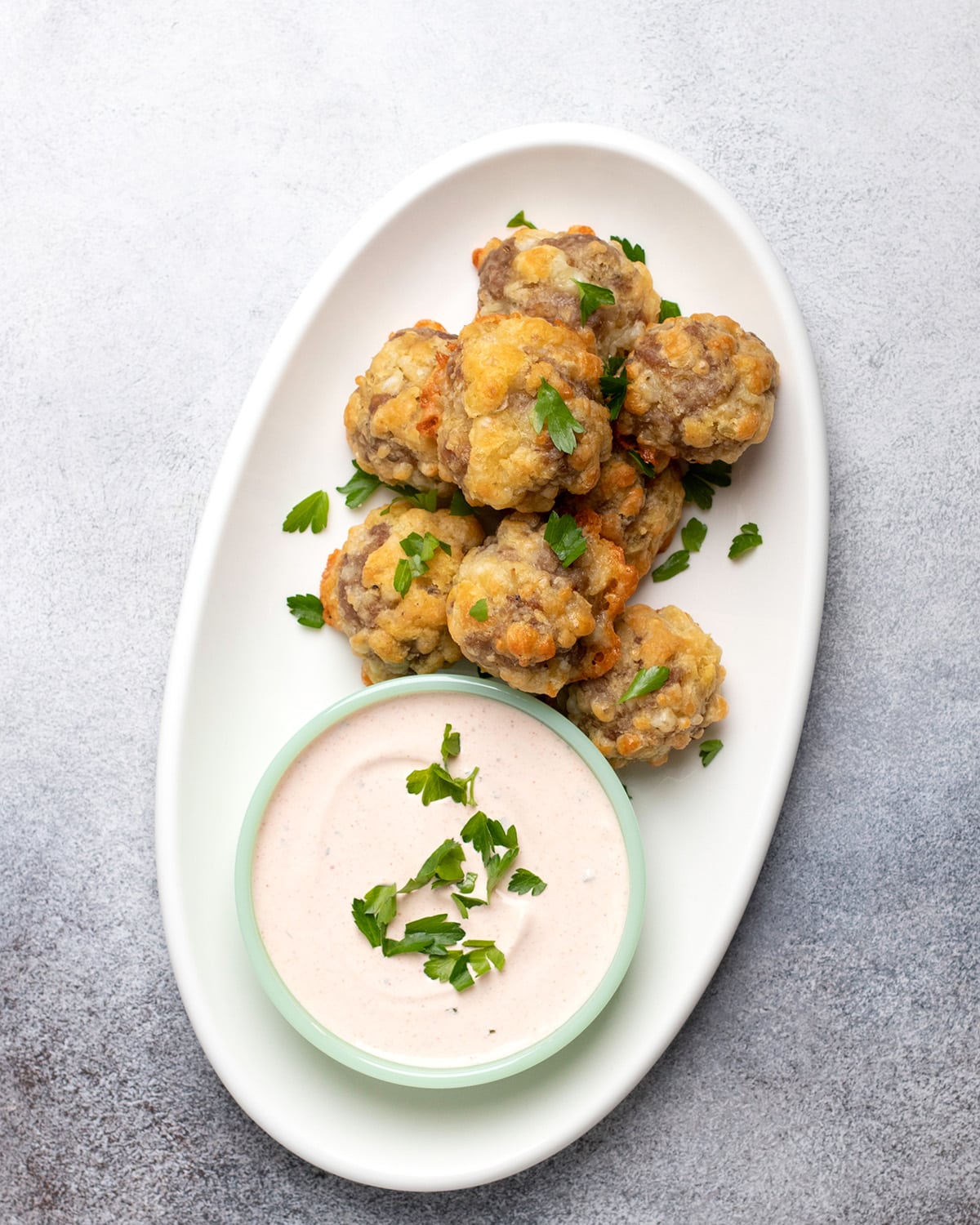 Overhead image of white oval platter with sausage balls and dipping sauce