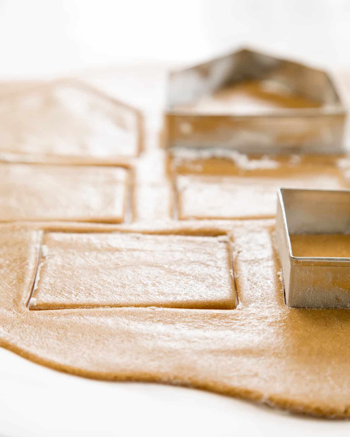 A close up of gingerbread cookie dough with cookie cutters