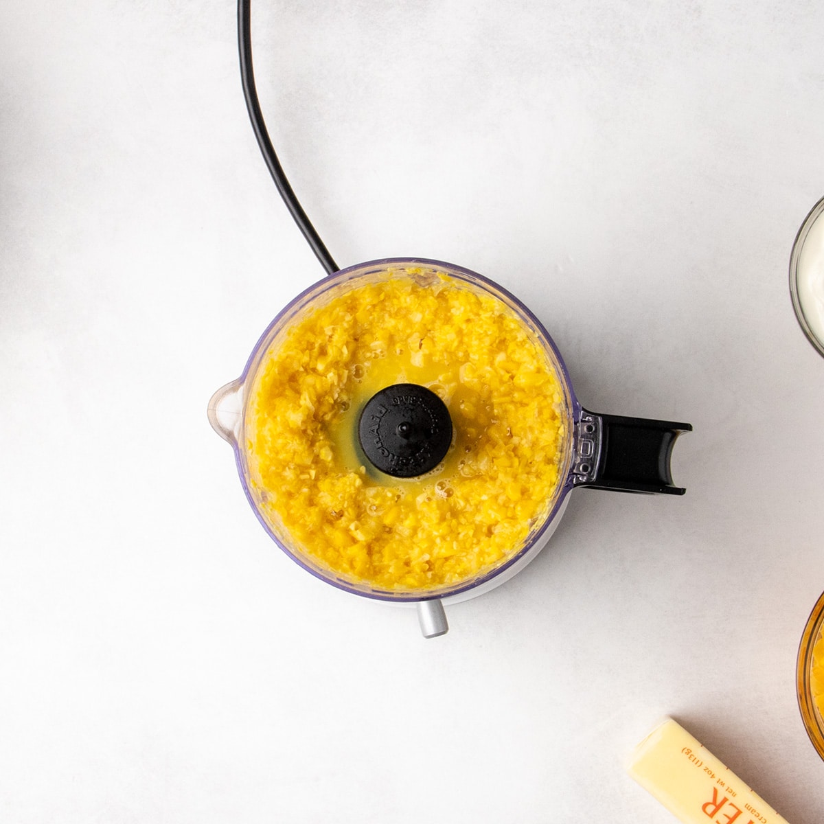 Chopped canned corn in the bowl of a mini food processor.