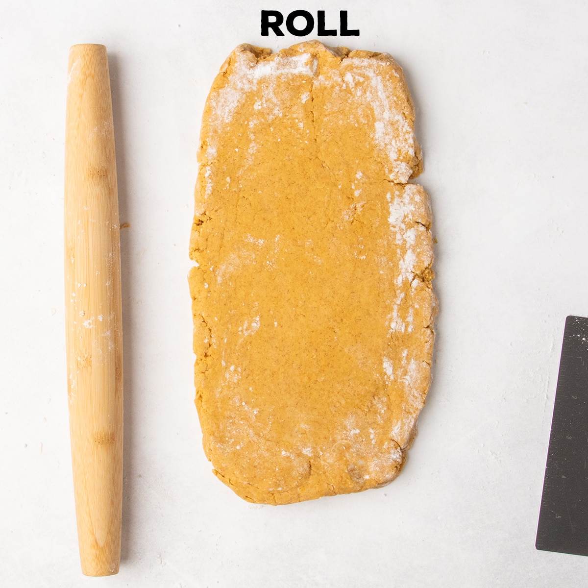 Orange dough is rolled into a long rectangle beside a wooden rolling pin beneath the word “ROLL.”