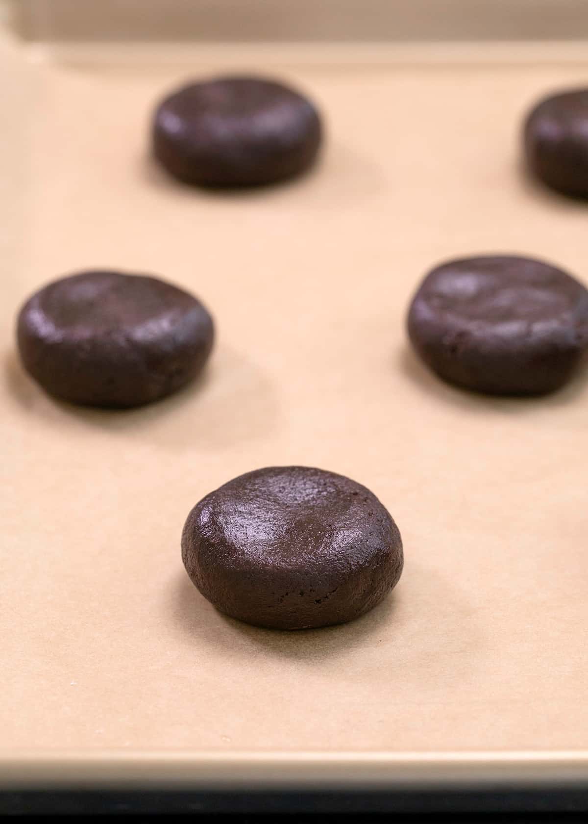 Shaped raw chocolate crinkle cookie dough on brown paper