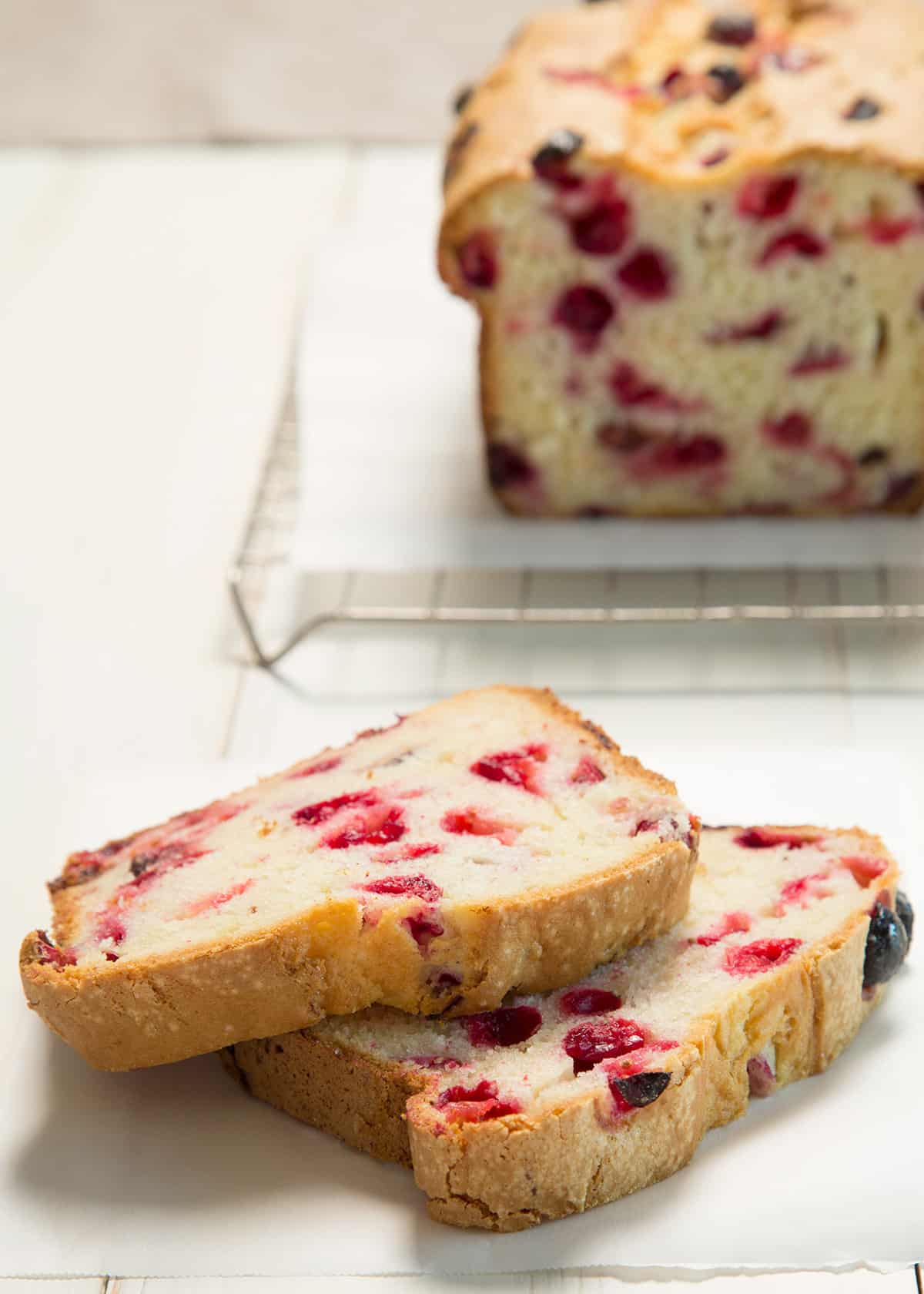 A close up of 2 slices of cranberry bread on a white background
