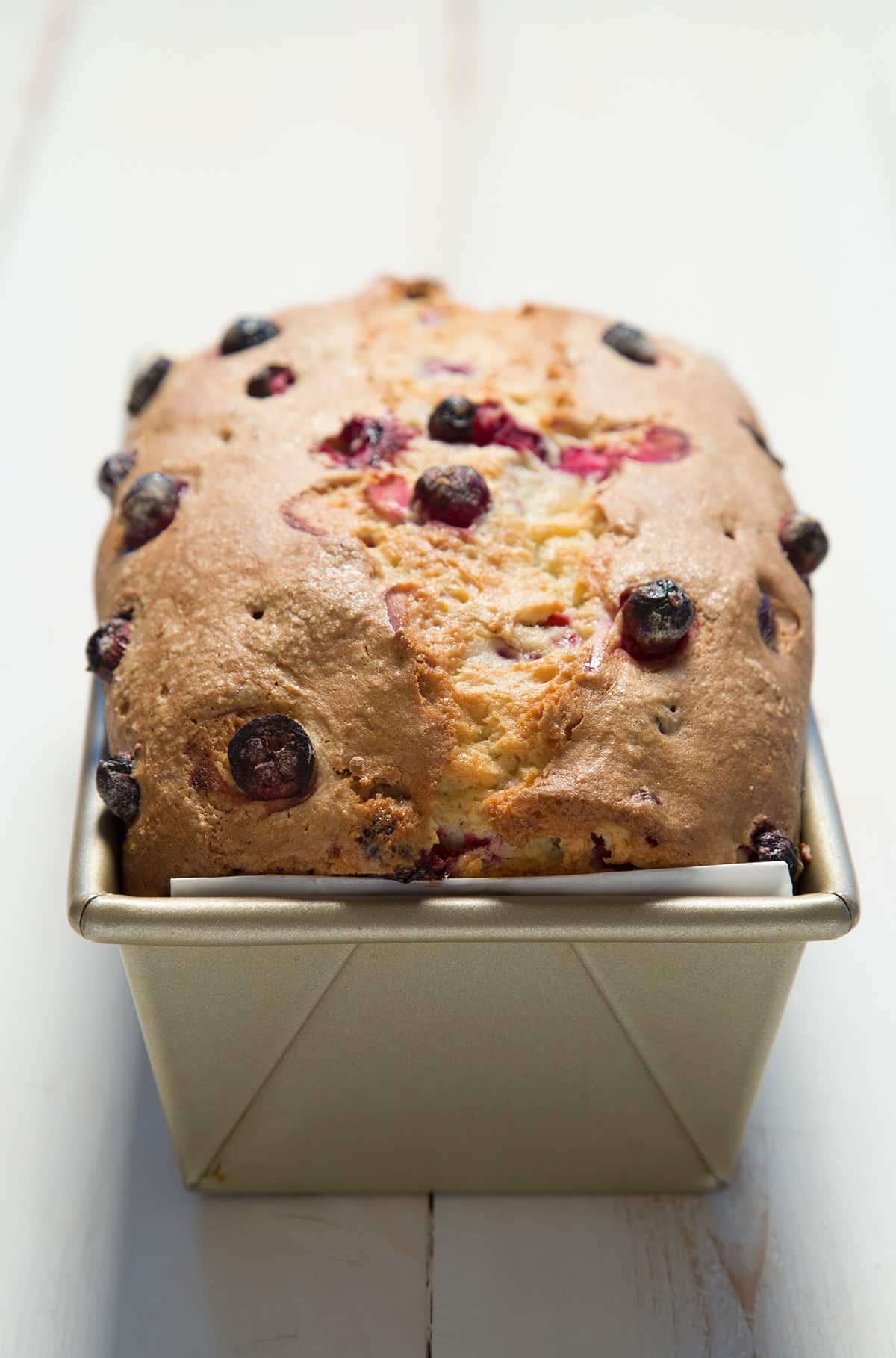 A close up of the top of the cranberry bread in a loaf pan.